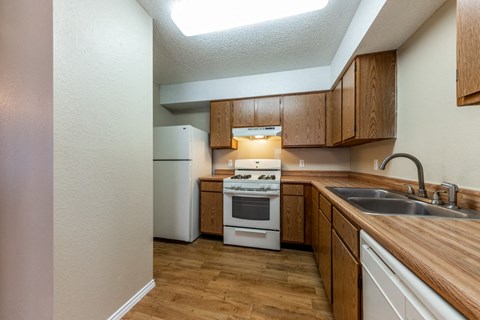 a kitchen with wooden cabinets and white appliances and a sink